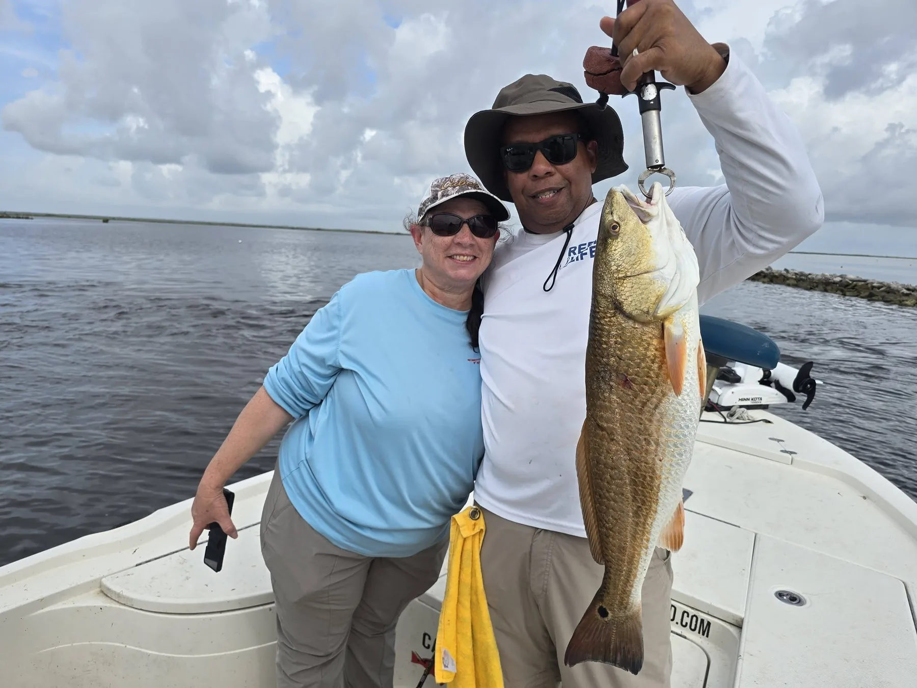 Happy guests holding a large redfish