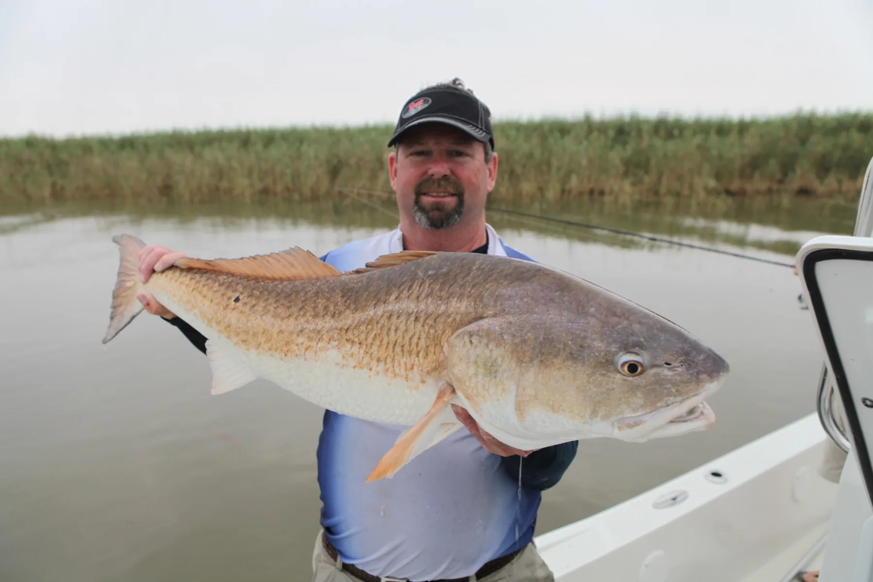 Captain Maurice d’Aquin holding a large redfish on his boat